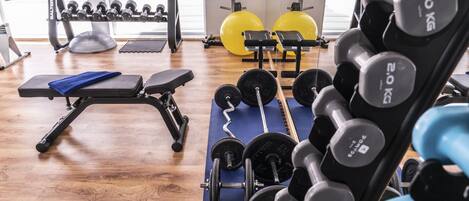 A gym with weightlifting equipment, exercise balls, and a bench.