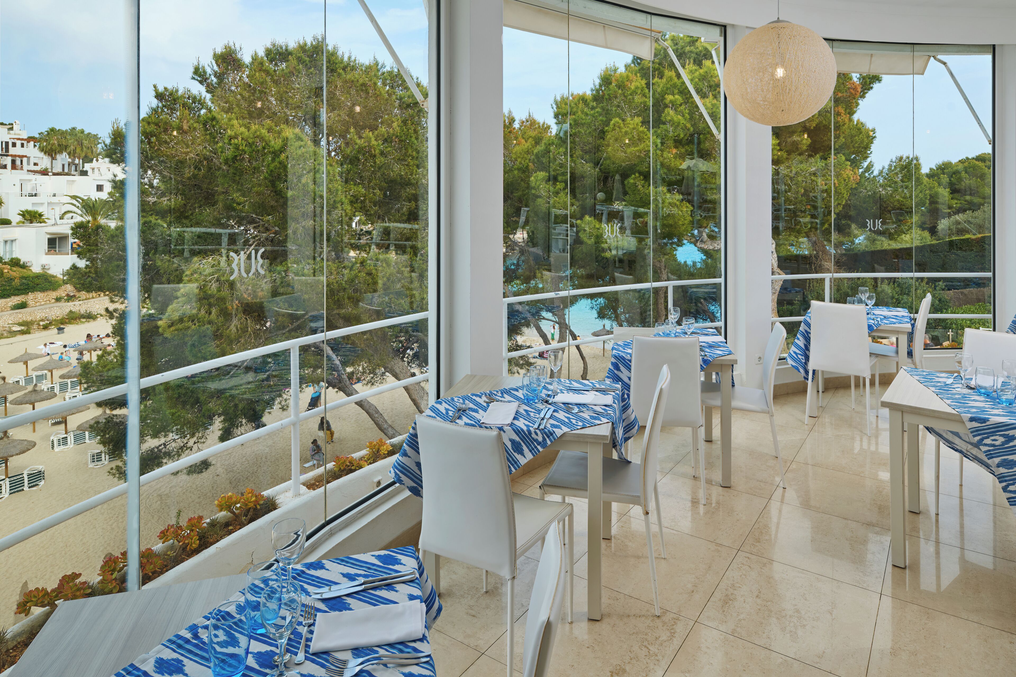 Un restaurante con terraza al aire libre que da a una playa y una piscina.
