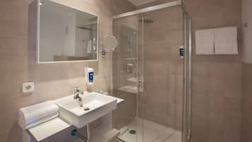A modern bathroom with a glass-enclosed shower, a sink with a mirror, and a towel rack.