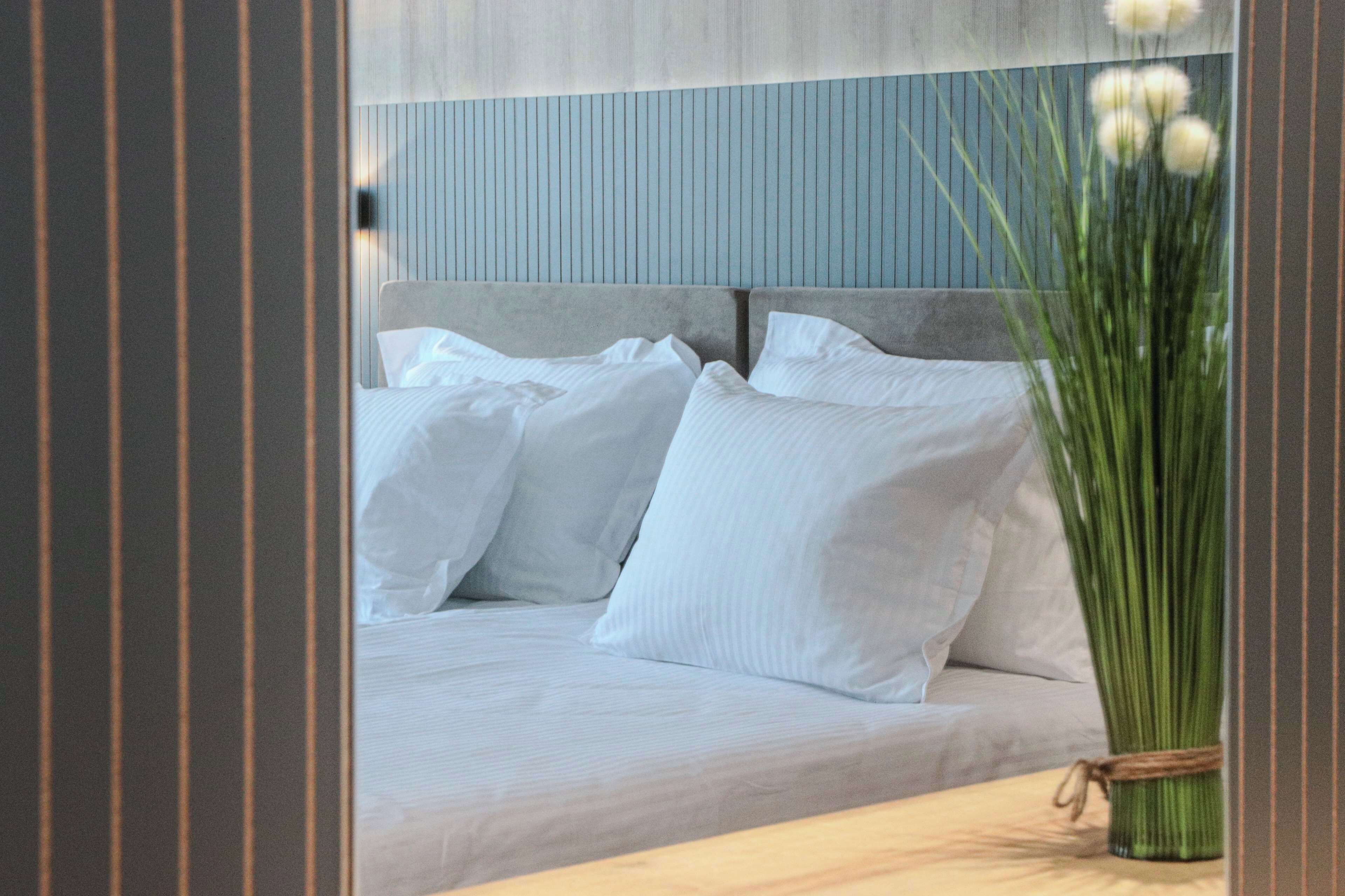 A bed with white linens and a headboard against a blue wall.