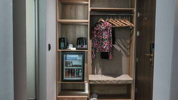 A walk-in closet with shelves, a hanging rack, and a mini-fridge.