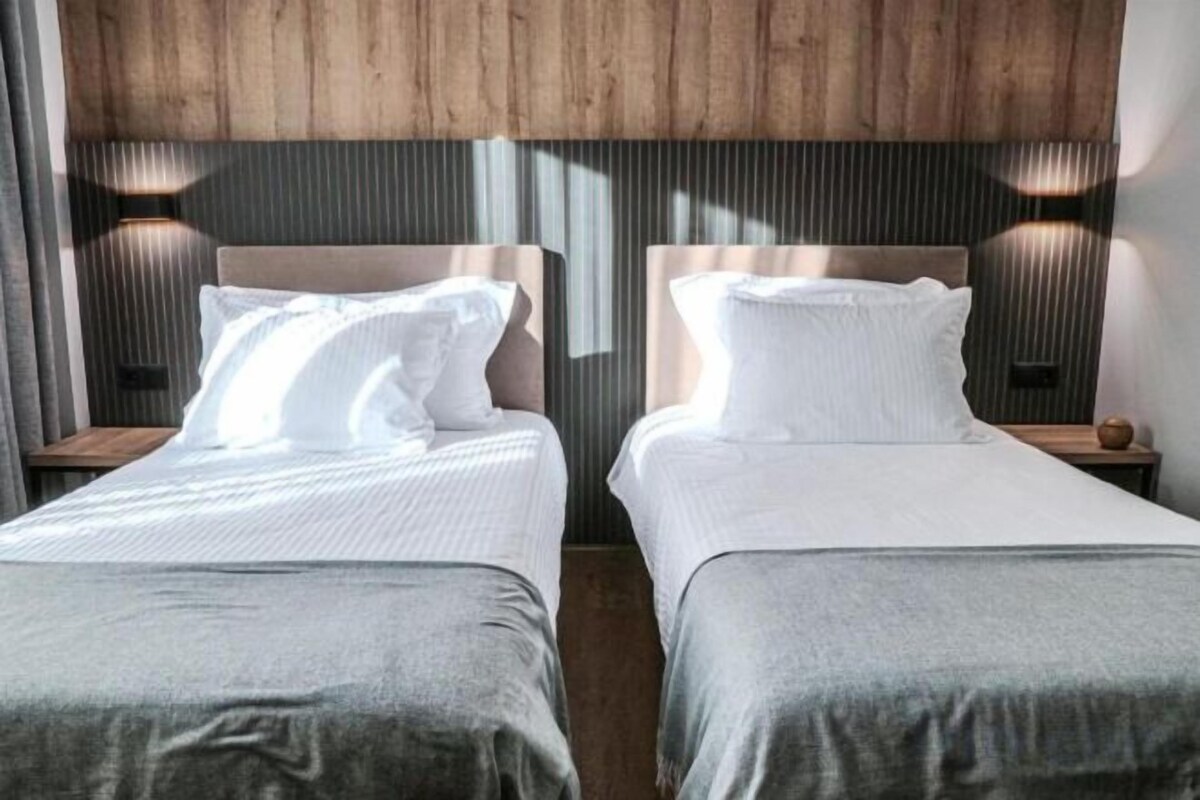 Two twin beds with headboards, a wooden ceiling, and wall-mounted lamps.