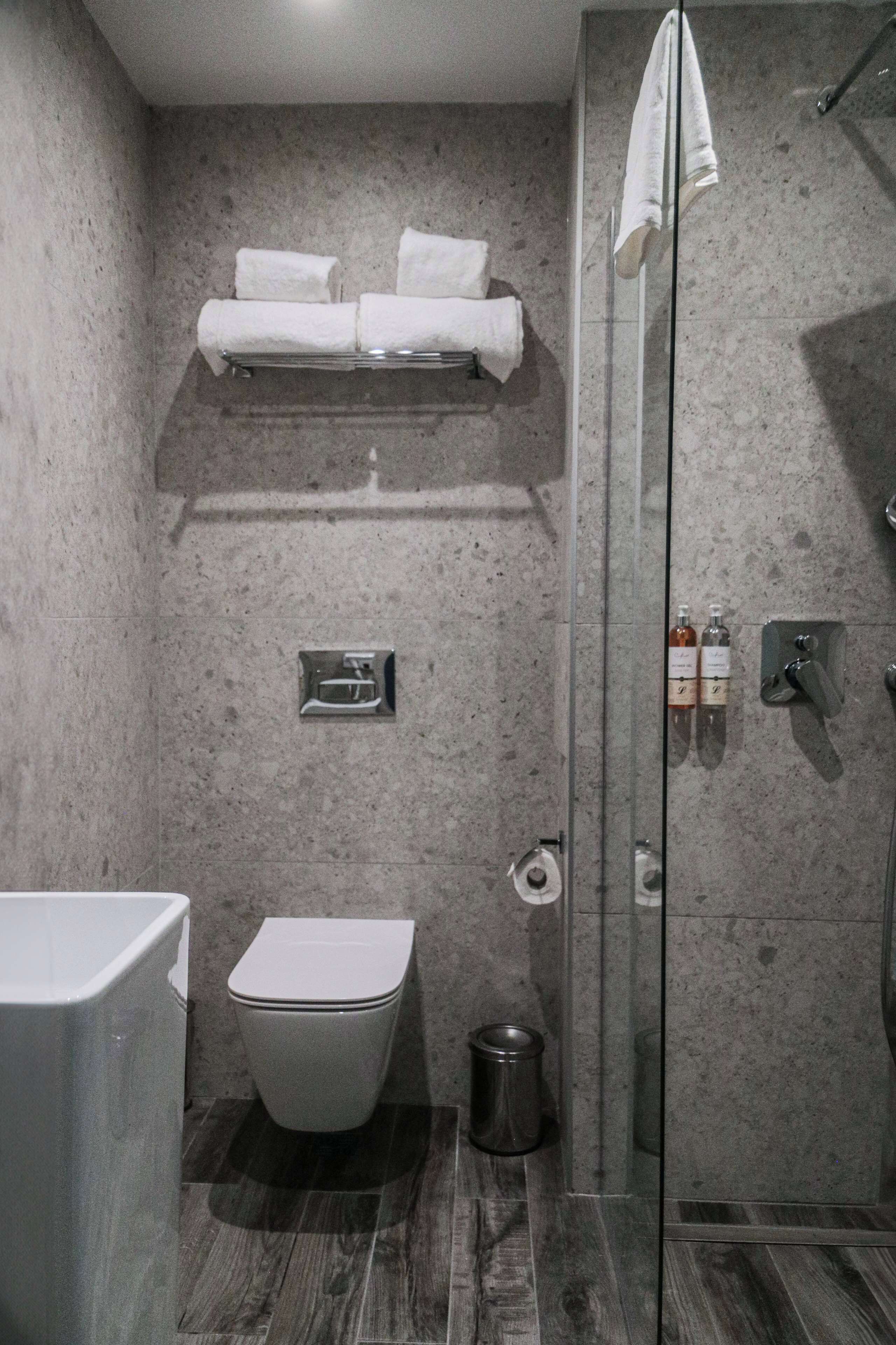 A modern bathroom with a toilet, a glass shower enclosure, and a towel rack.