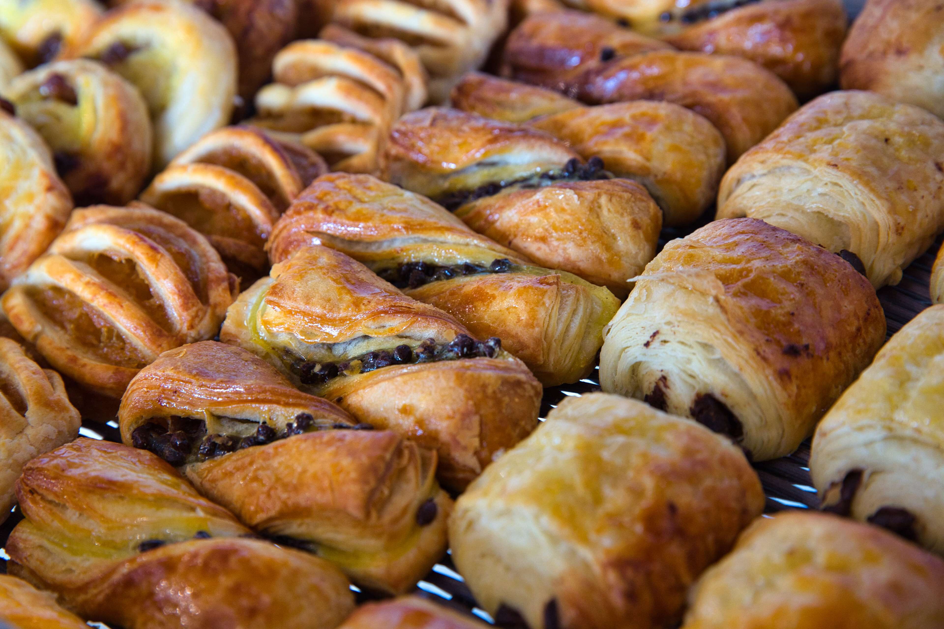 A variety of pastries, including croissants and chocolate-filled pastries, displayed on a rack.