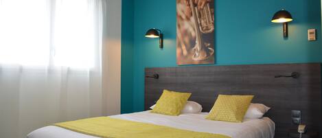 Habitación de hotel con una cama grande, dos lámparas de pared, un cuadro y un teléfono en la mesita de noche.