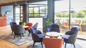 Un vestíbulo de hotel con mobiliario moderno, un mostrador de recepción y ventanas amplias que ofrecen vistas al exterior.