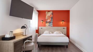 A hotel room with a bed, desk, chair, and a TV mounted on the wall.