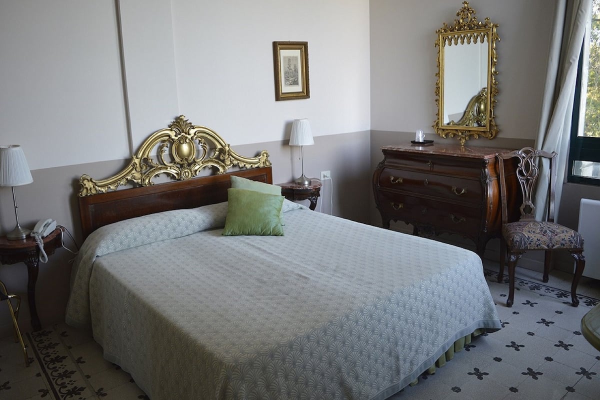 Une chambre bien rangée, avec un grand lit, une commode, une chaise et un miroir.