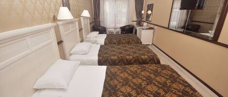 A hotel room with two beds, a desk, a chair, a TV, and a window with curtains.