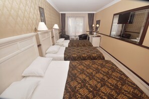 A hotel room with two beds, a desk, a chair, a TV, and a window with curtains.