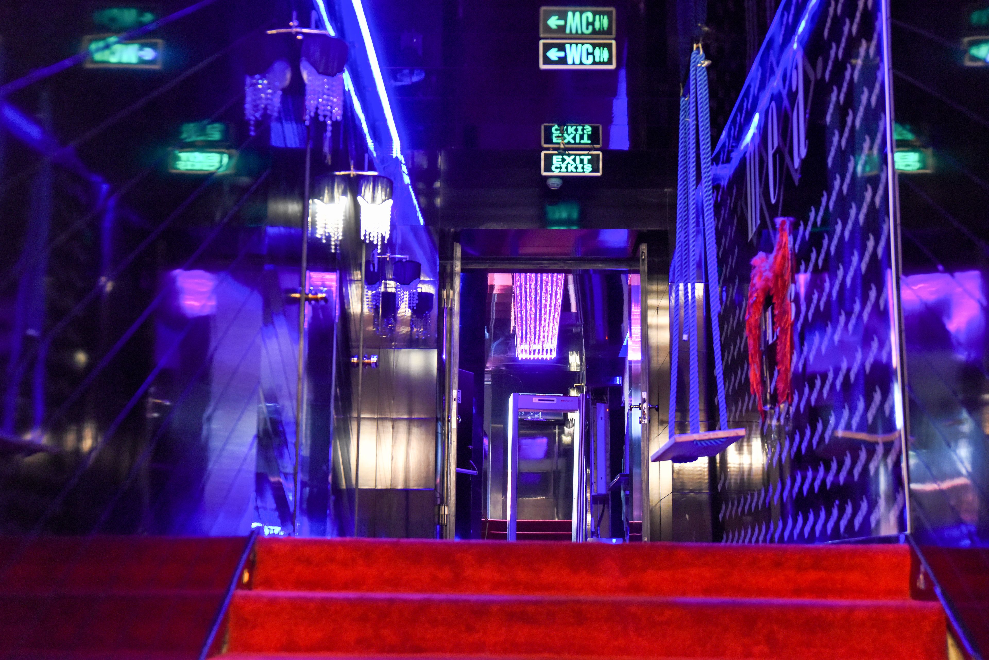 Eine hell erleuchtete Treppe mit Neonhinweisschildern, die den Weg zum Veranstaltungsraum und zur Toilette weisen.