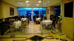 A restaurant with tables set for dining, a glass partition, and decorative elements. - Topkapi Inter Istanbul Hotel (Istanbul)