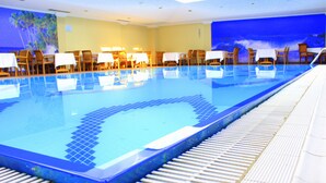 A swimming pool with tiled edges, surrounded by lounge chairs and tables, with a mural of a tropical scene on the wall. - Topkapi Inter Istanbul Hotel (Istanbul)