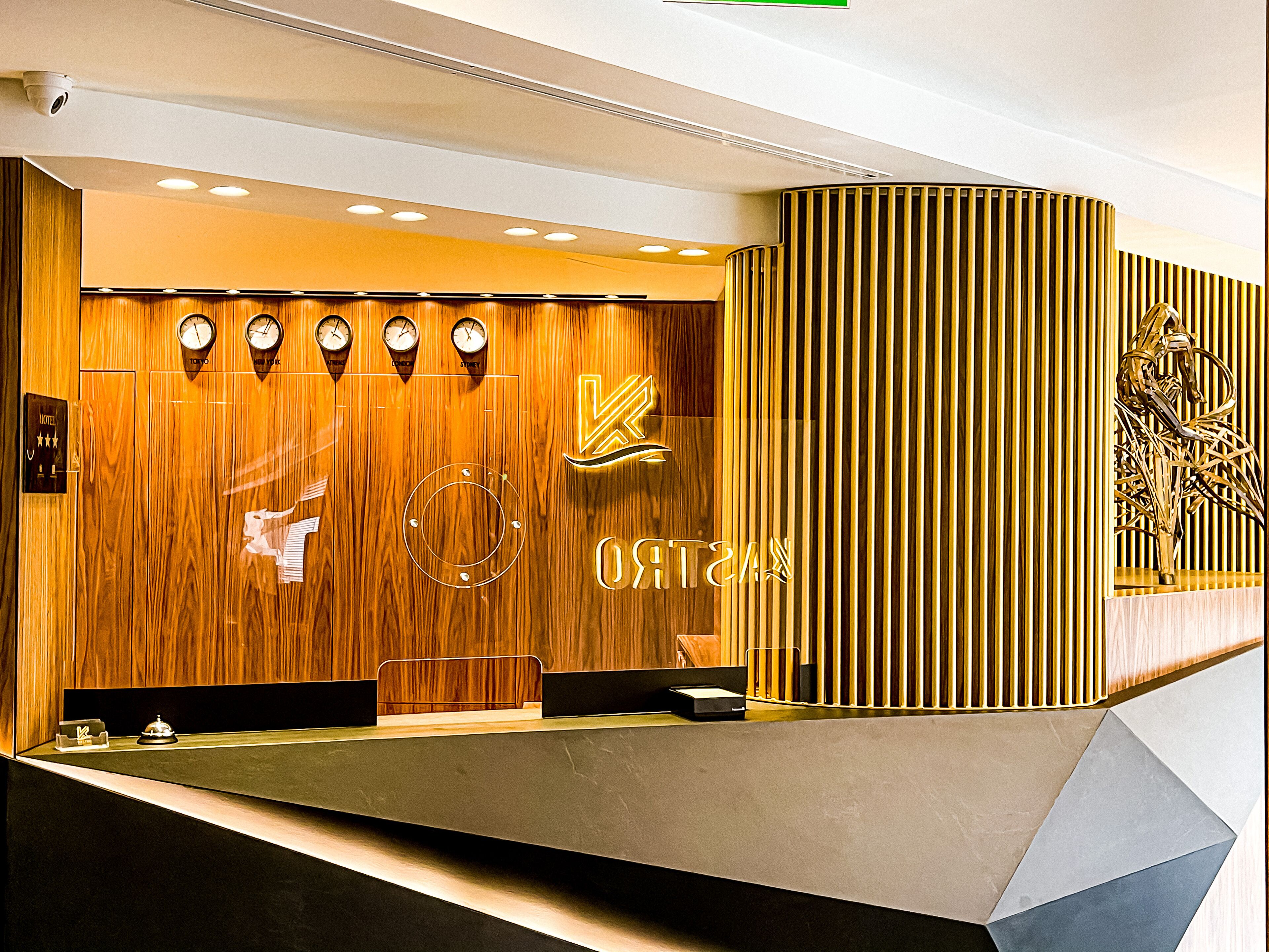 A reception desk with a wooden panel wall, a neon sign, clocks, and a reception counter.