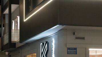 A modern hotel with a prominent 'KASTRO' sign, a visible staircase, and a glimpse of the interior through the windows.