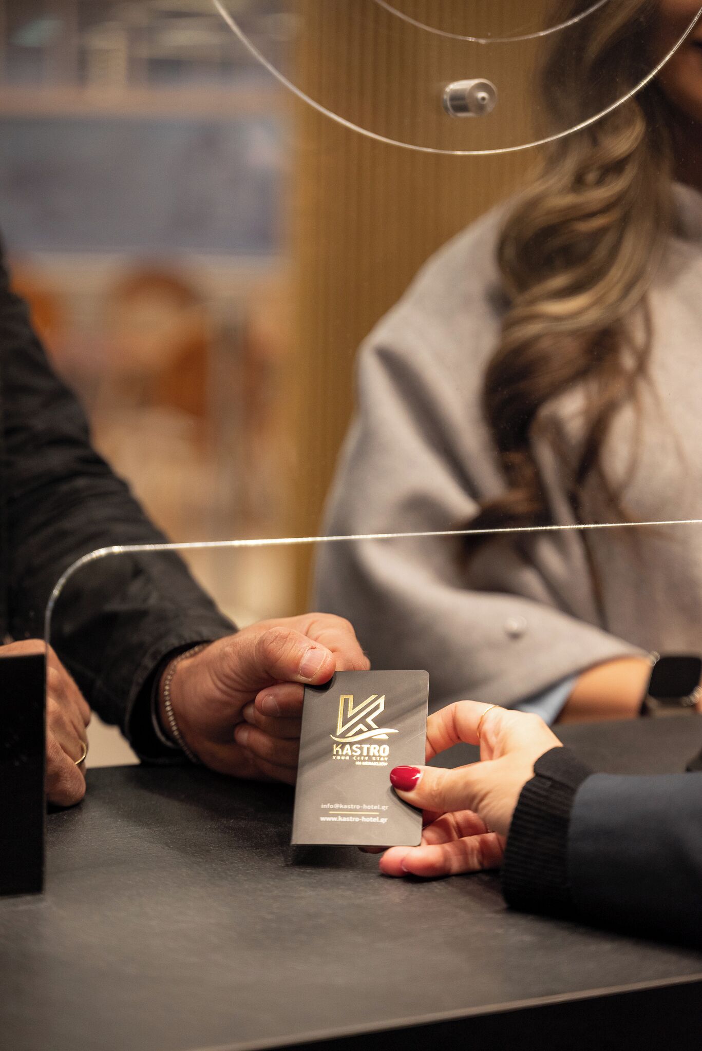 A person holding a business card with the text "HASTRO HOTEL" and a website address.