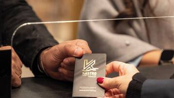 A person holding a business card with the text "HASTRO HOTEL" and a website address.