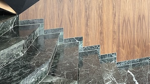 A modern staircase with dark marble steps and a wooden panel wall. - Kastro Hotel (Heraklion)