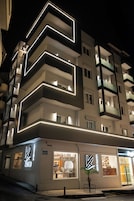 Um hotel moderno com fachada geométrica marcante e contornos iluminados em neon.