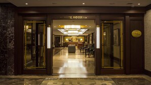 Um saguão de hotel com balcão de recepção, área de estar e piso de mármore polido.