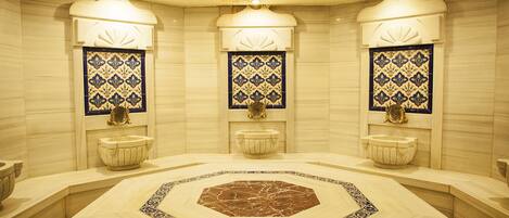 A bathroom with three sinks, a central octagonal marble floor, and decorative tiles on the walls.