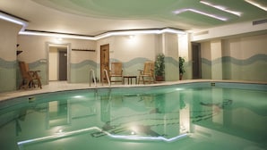 Uma piscina com revestimento de azulejos, cadeiras de madeira e um vaso de planta.