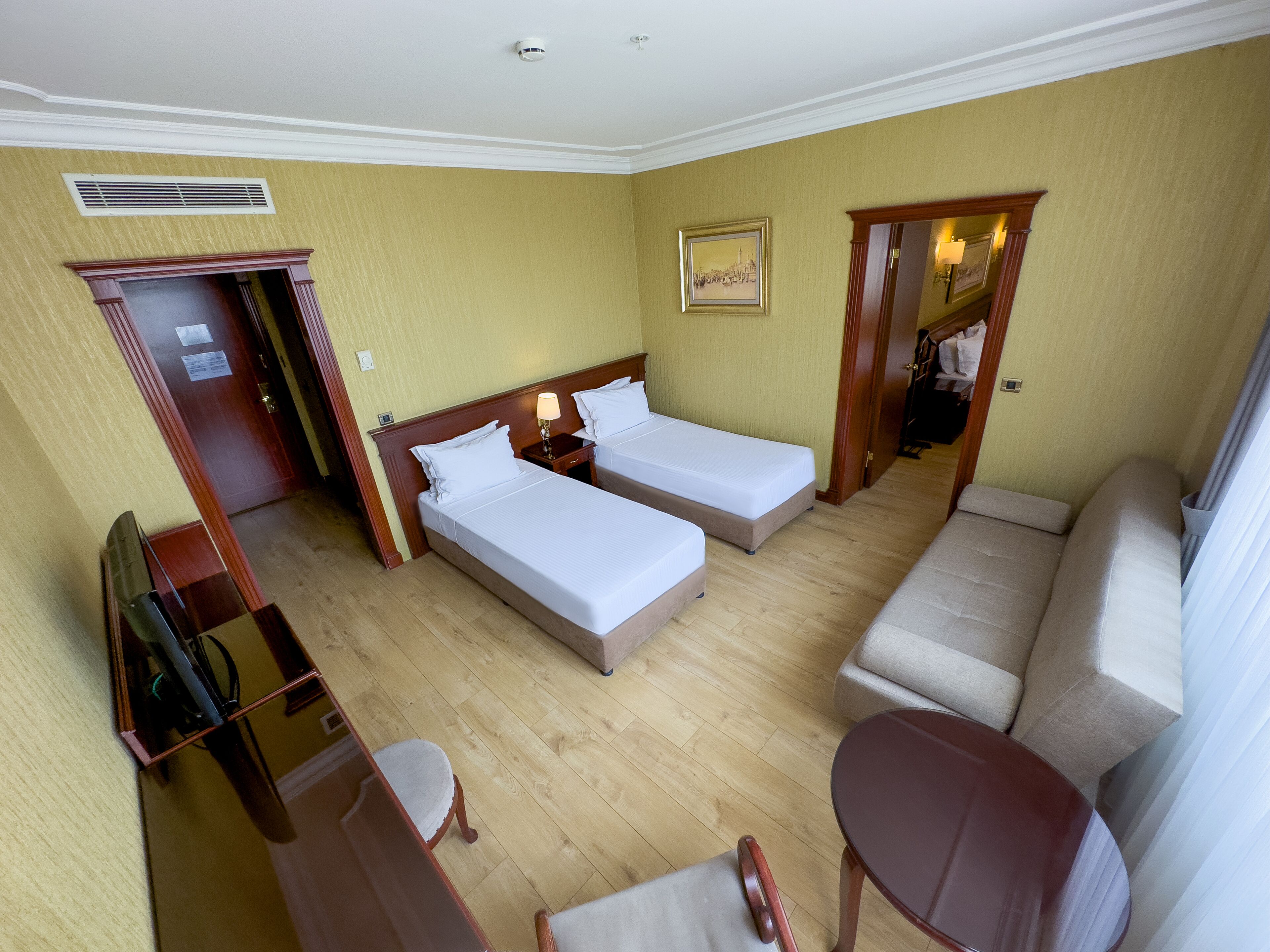 Una habitación de hotel con dos camas, un sofá, un escritorio y una silla.