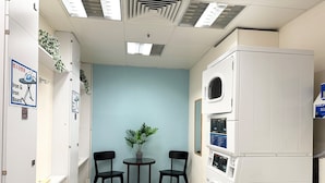 A laundry room with a washing machine, two chairs, a small table, and a potted plant. - Holiday Inn Express Causeway Bay Hong Kong by IHG (Hong Kong)