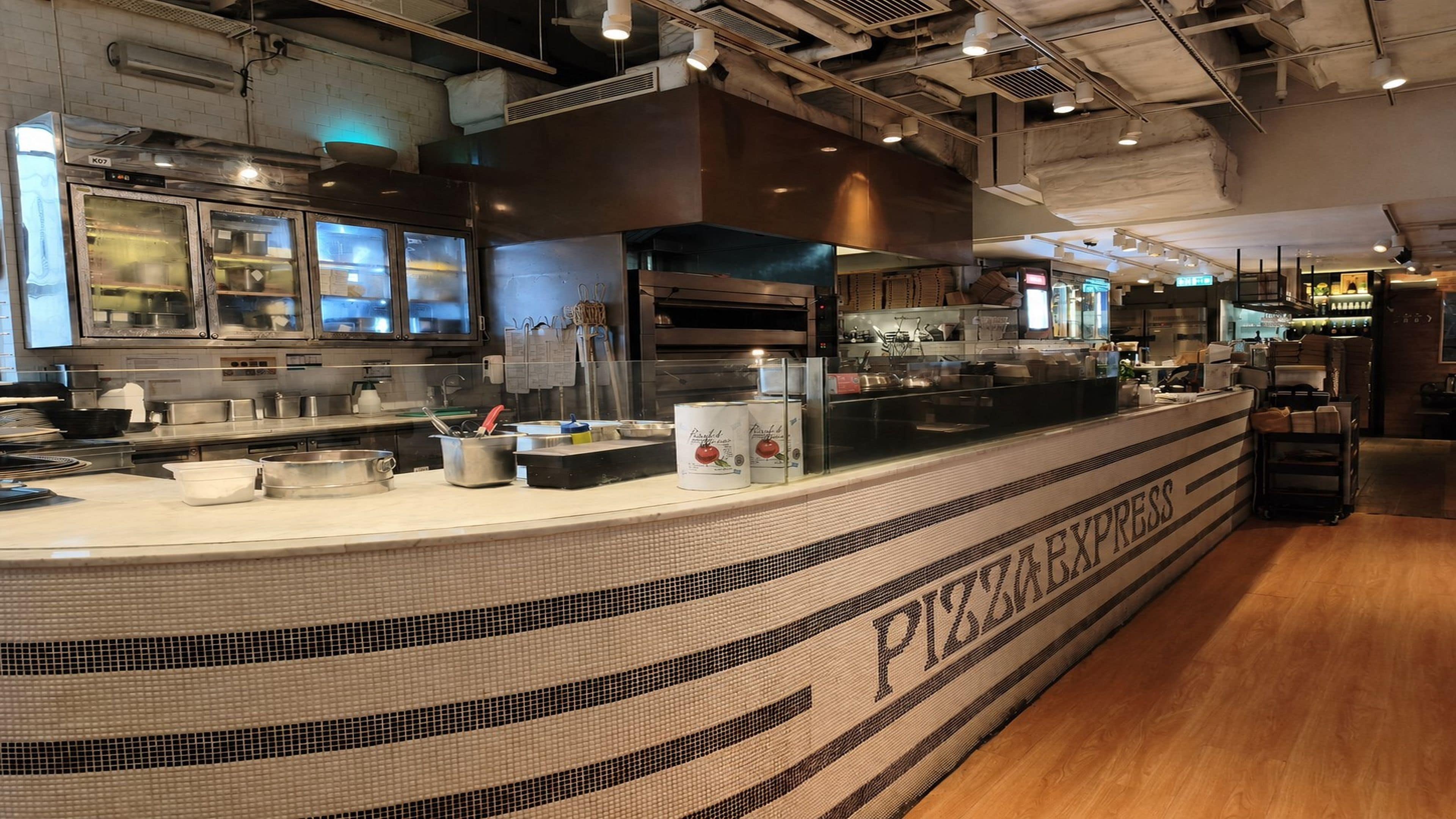 A kitchen area with a counter labeled 'PIZZA EXPRESS' and various cooking equipment.
