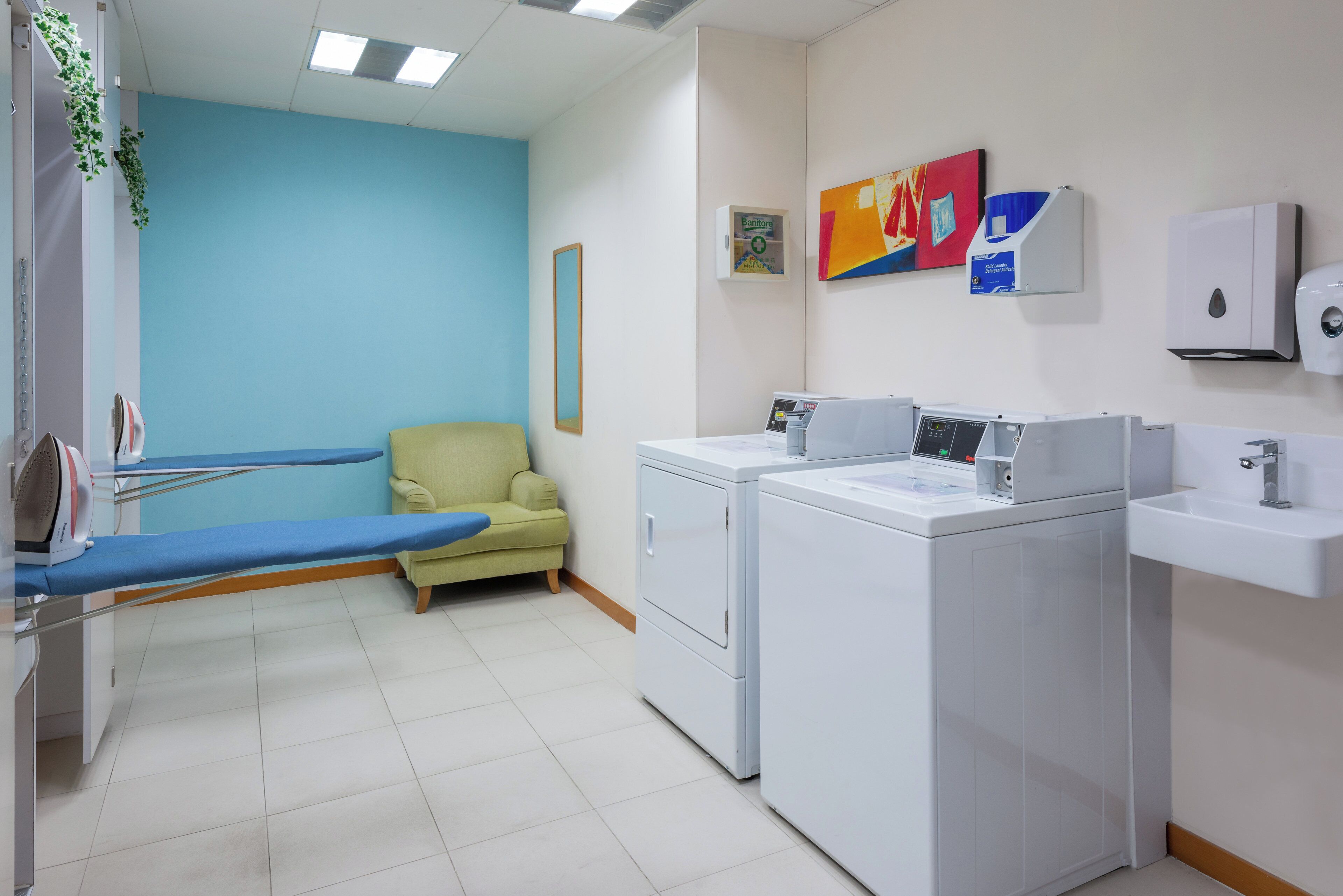 A clinical setting with medical equipment, a chair, a washing machine, and a sink.