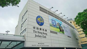A building with a sign for The Hong Kong Jockey Club and a Happy Valley Racecourse.