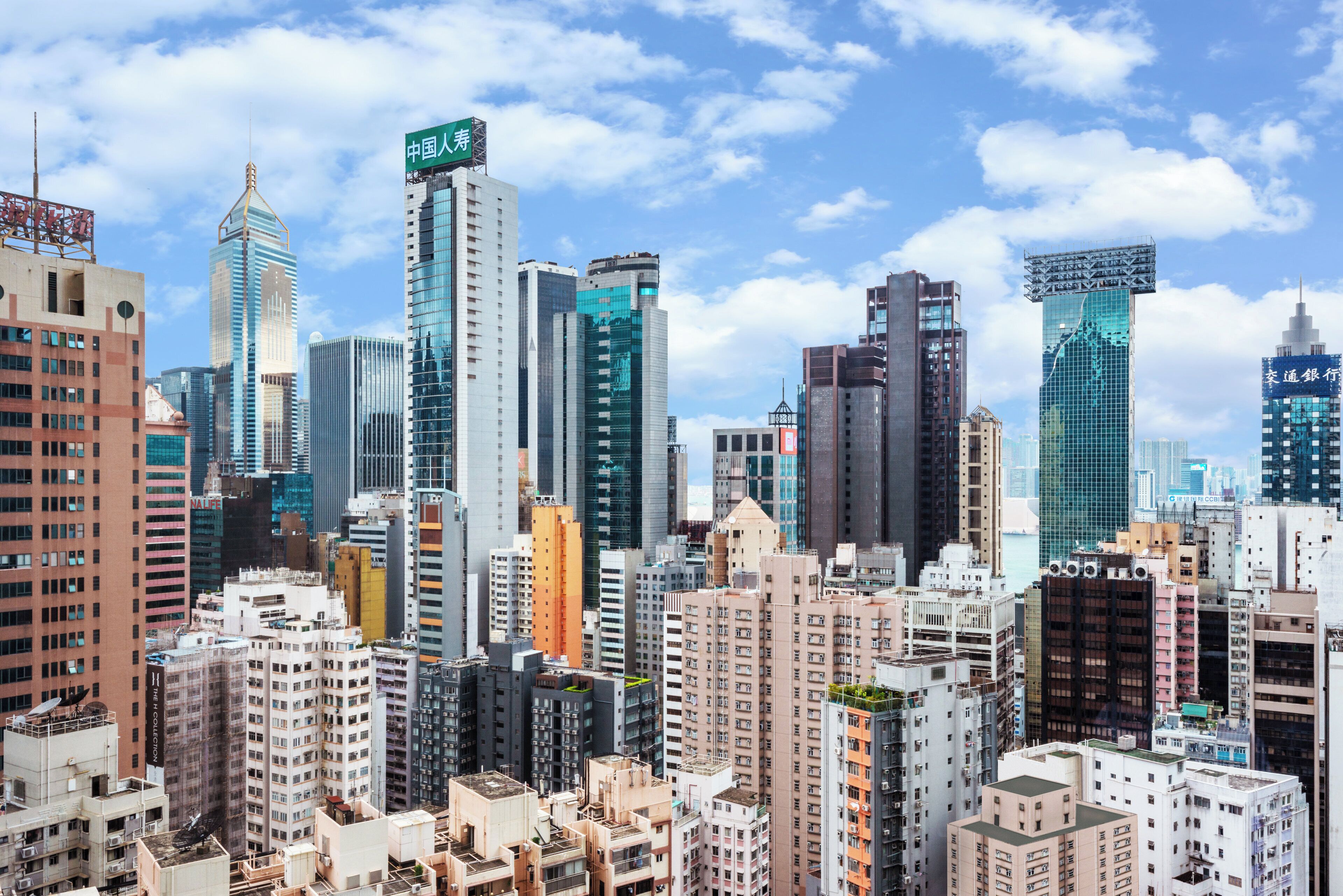A cityscape with high-rise buildings, including a prominent building with a sign in a foreign language.