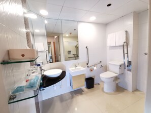 Et moderne badeværelse med en glashylde, vask, toilet og bruseområde.