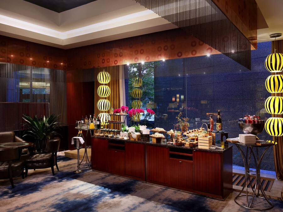 Um hall de hotel moderno com área de bar, assentos e iluminação decorativa.