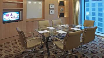 A conference room with a glass table, leather chairs, a television, a whiteboard, and a city view.