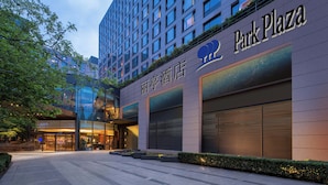 Un hotel moderno con un llamativo letrero de 'Park Plaza', que cuenta con un amplio frente de vidrio y una entrada bien iluminada.