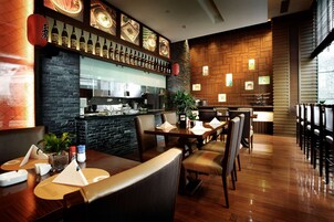 A restaurant with wooden flooring, a bar area, and a seating arrangement with tables and chairs.
