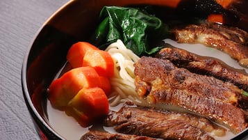 A bowl of ramen with various toppings including noodles, meat, and vegetables.