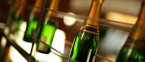 A row of green bottles with gold foil, likely containing champagne, displayed on a metal rack.