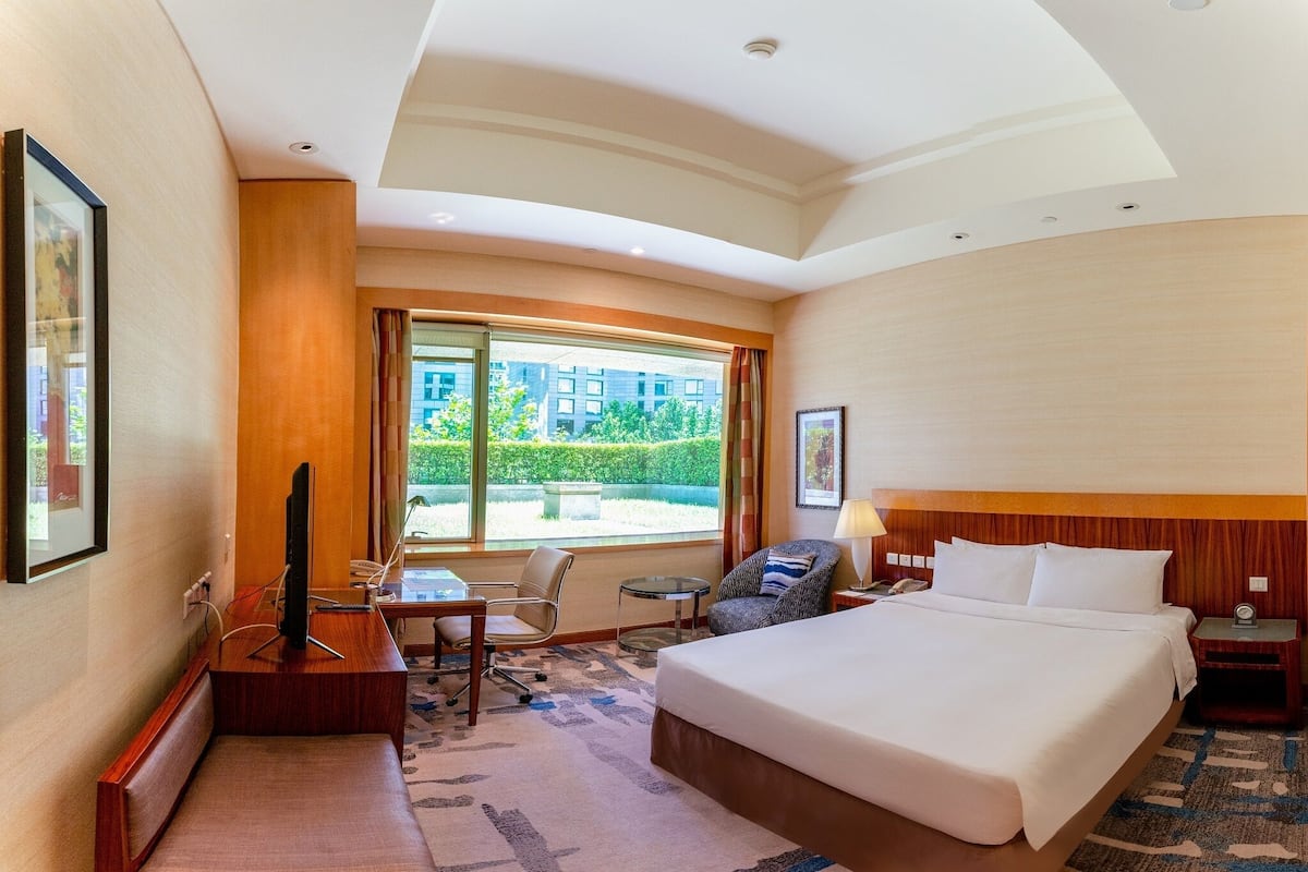 A hotel room with a large bed, a desk with a computer, a chair, and a TV.