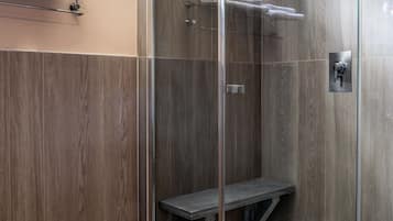Un box doccia moderno con porta in vetro, una panca integrata e un porta asciugamani sopra.