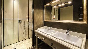 Un bagno con un grande specchio, due lavandini, una doccia e un portasciugamani.