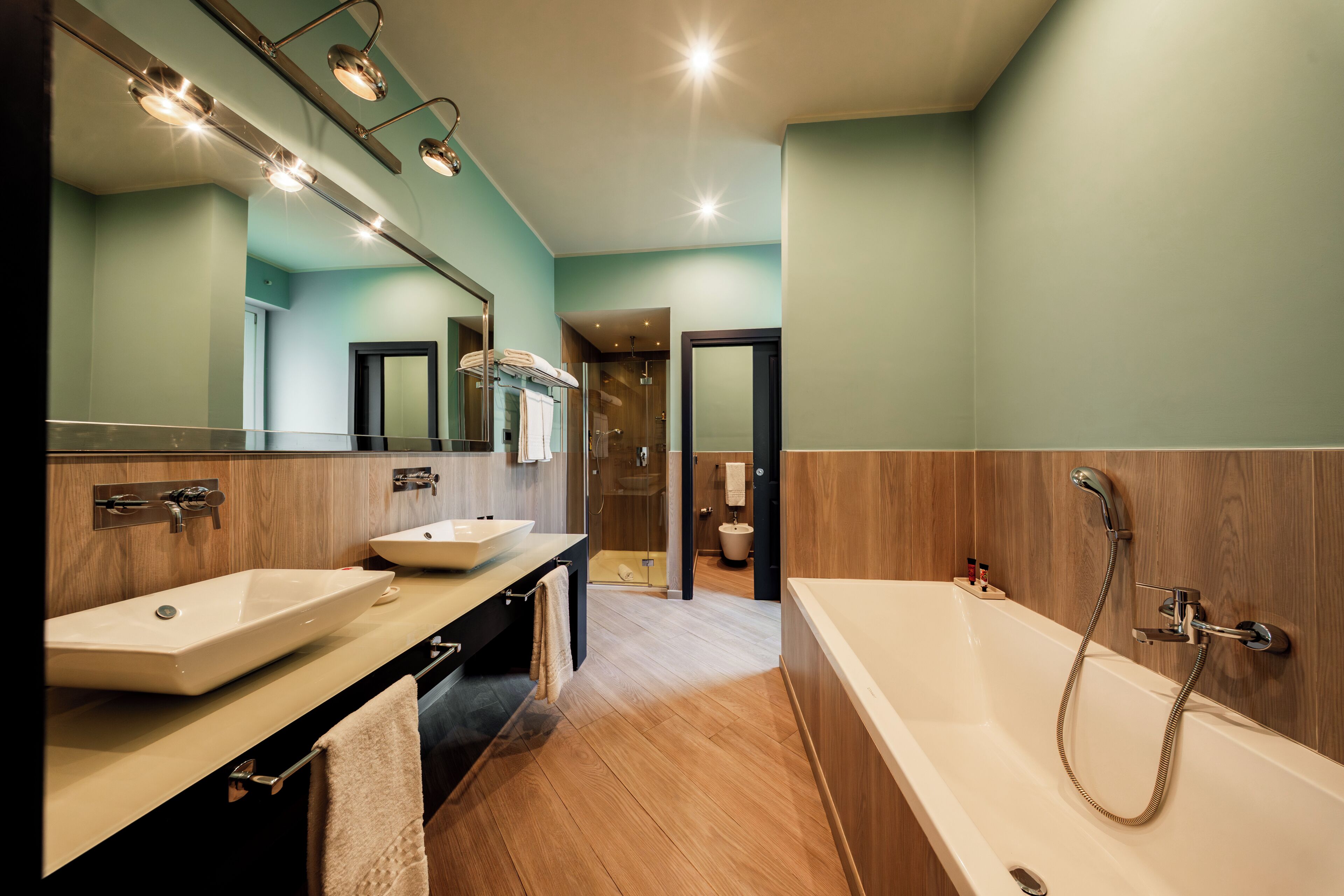 A modern bathroom with a large bathtub, two sinks, and a glass shower enclosure.