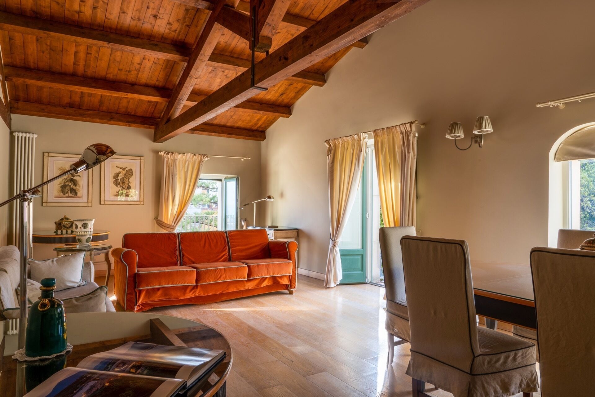 Un salón espacioso con techo de madera, un sofá, una silla y una mesa.