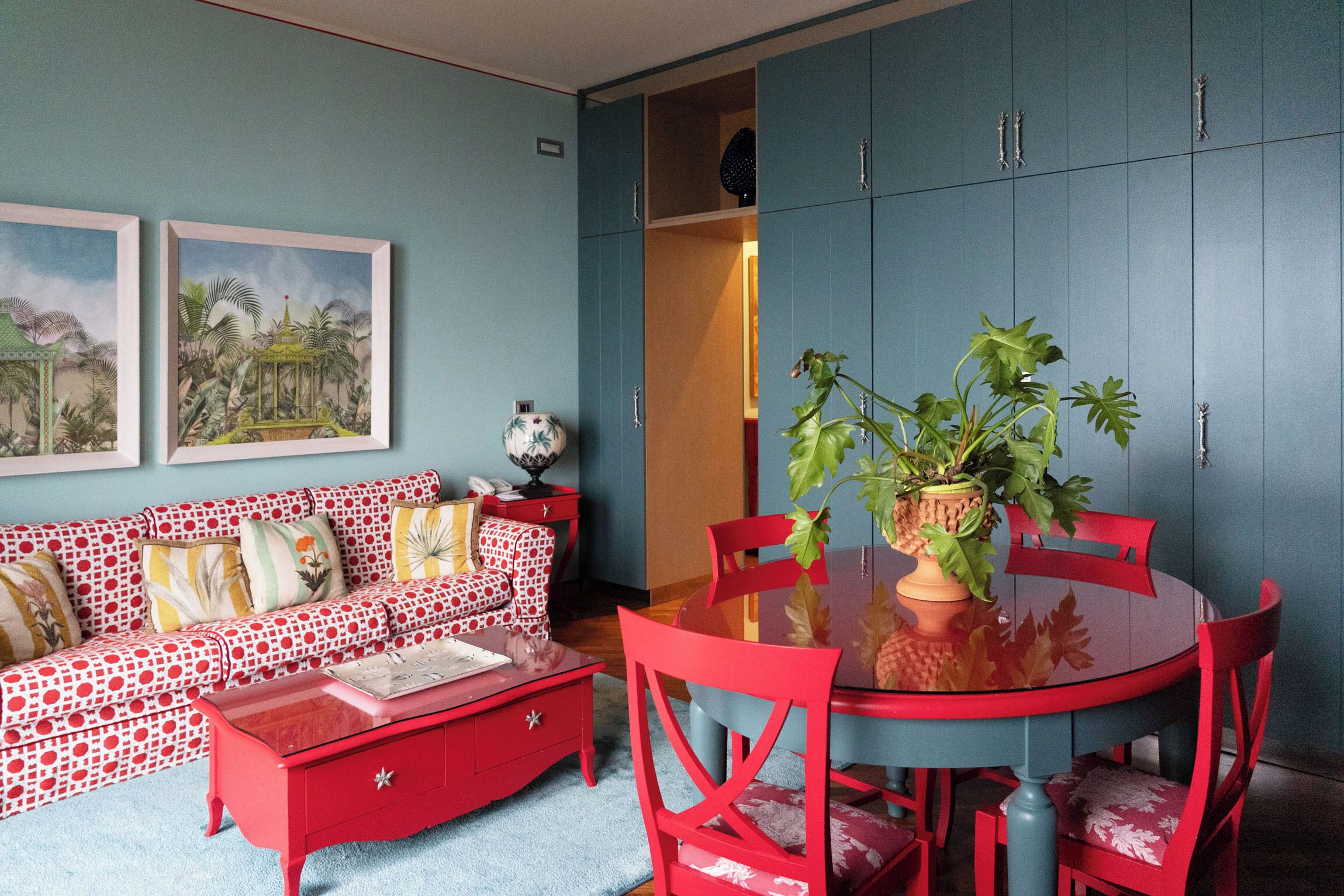 Una habitación con un sofá rojo, un comedor rojo y un armario azul.