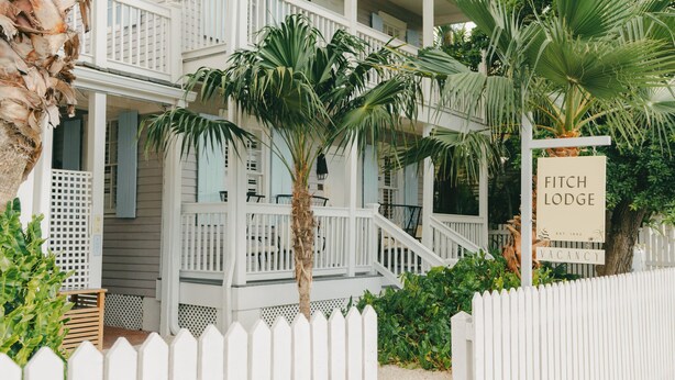 A two-story white building with a porch and a sign indicating it is a vacant property named 'Fitch Lodge'. - Fitch Lodge - Key West Historic Inns (Key West)