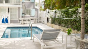 A poolside area with a lounge chair, a small table, and a pool. - Fitch Lodge - Key West Historic Inns (Key West)