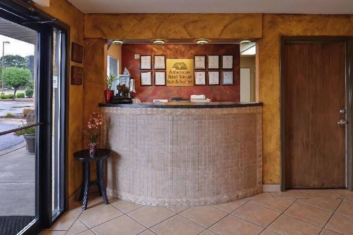 A reception area with a tiled counter, framed certificates, and a door to the right.