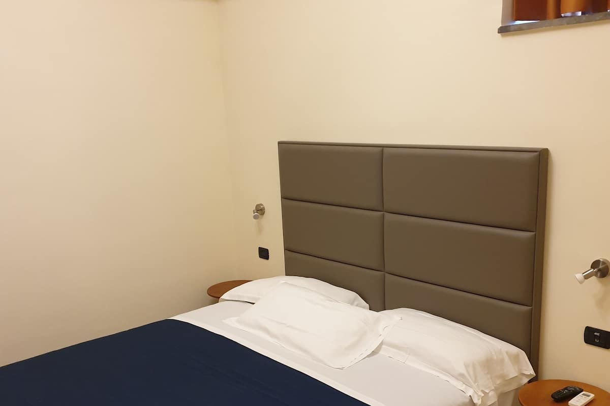 A hotel room with a bed, a bedside table, and a nightstand.