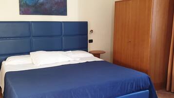 A bedroom with a large bed, a wooden wardrobe, and a small round table.